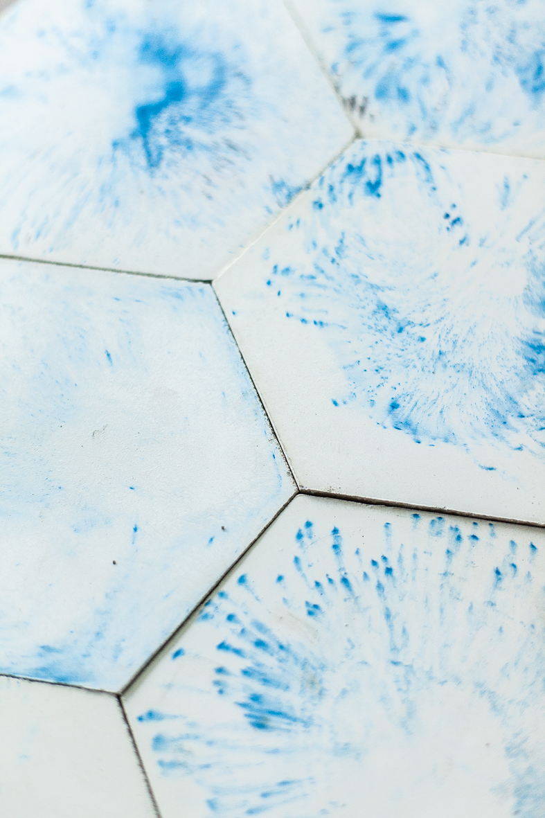 Kompozycja z sześciokątnych białych kafelków z niebieskimi rozmytymi wzorami przypominającymi ślady po kapiącej wodzie