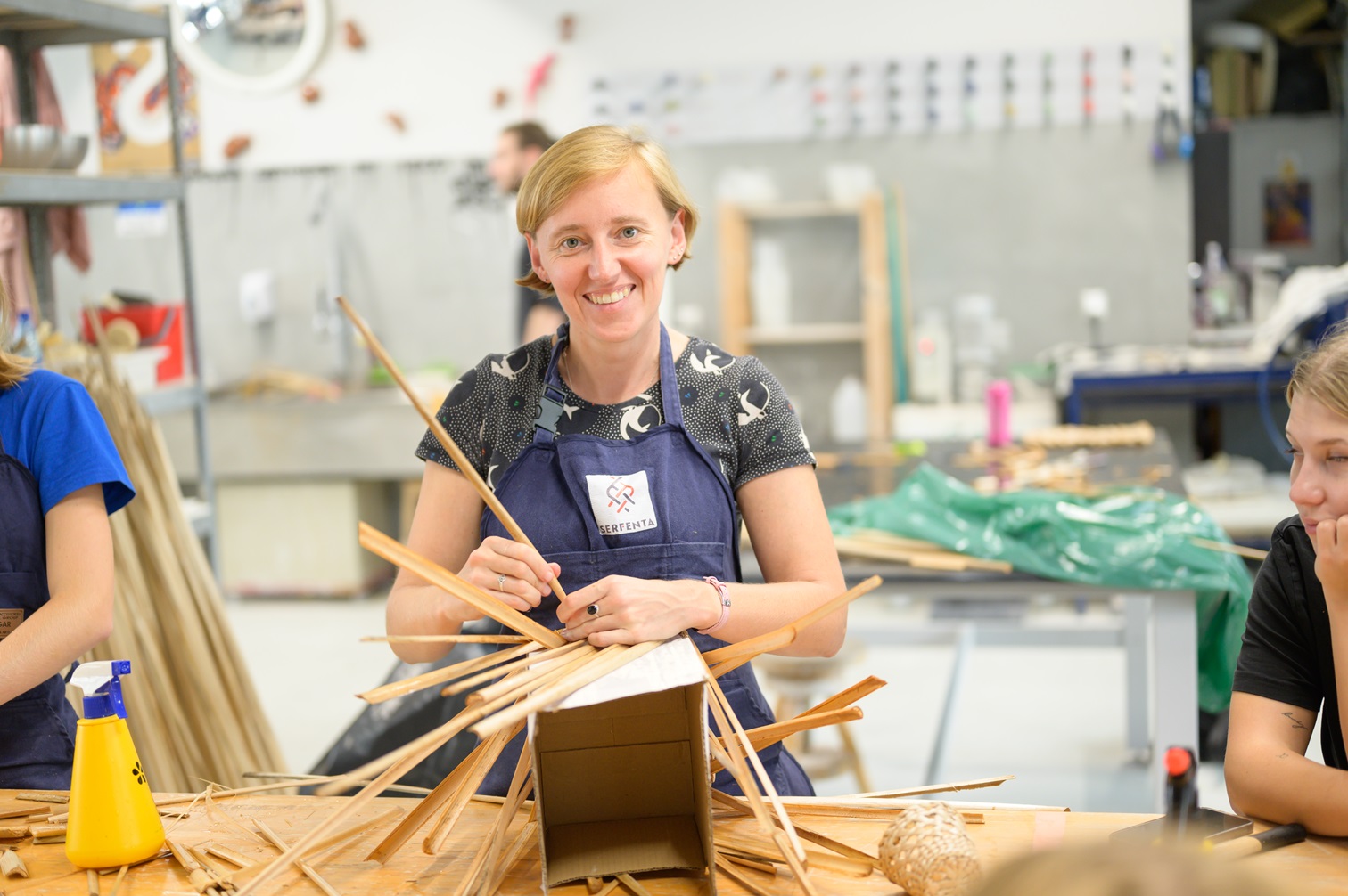 Workshop instructor holding pieces of bulrush in hand, displayed on a cardboard box | Photo: School of Form