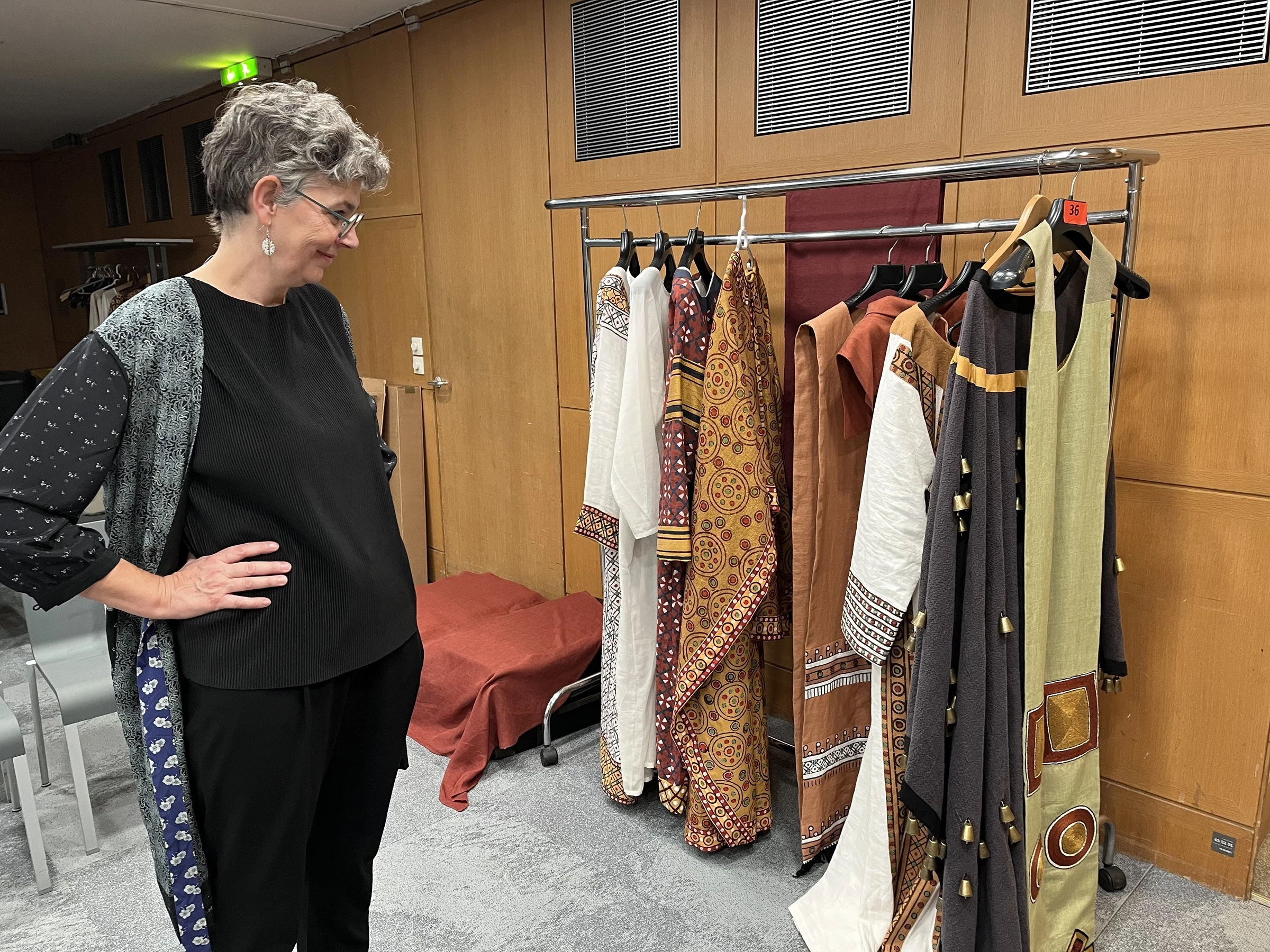 Agnieszka Jacobson Cielecka looking at reconstructed costumes from Faras on a hanger