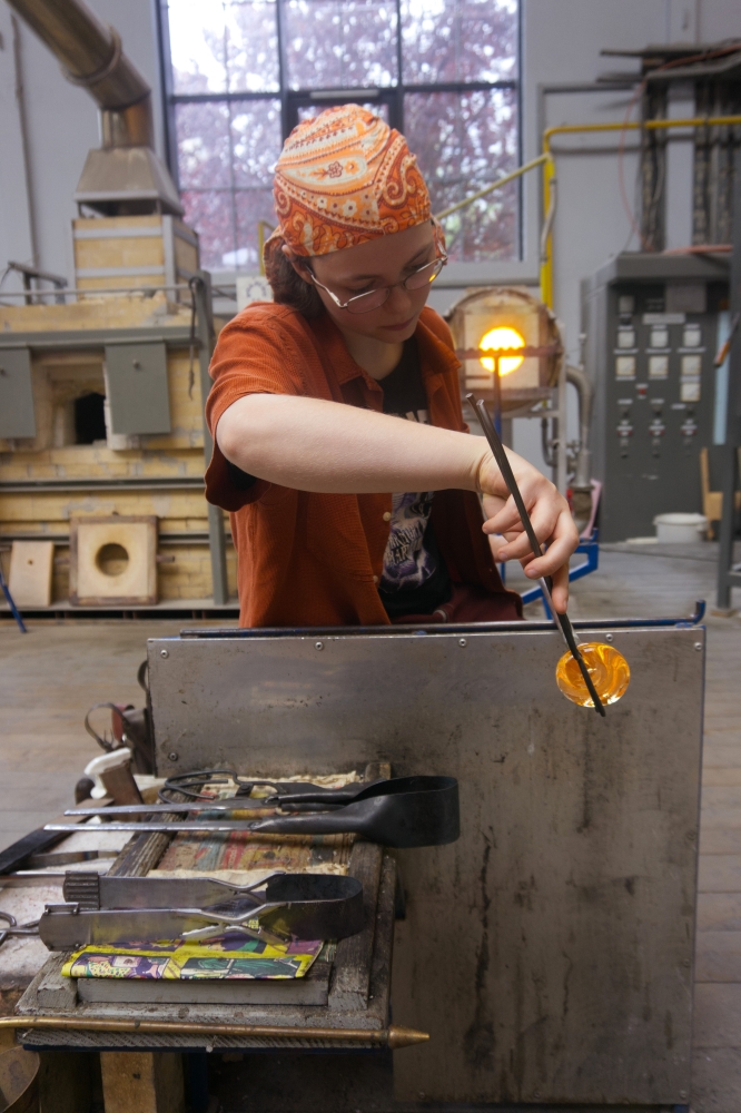 A young woman at work using glassblowing tools of her own design
