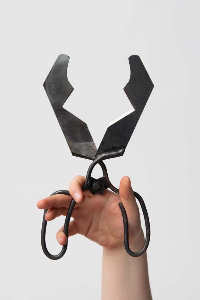 A hand holding a glassblowing tool