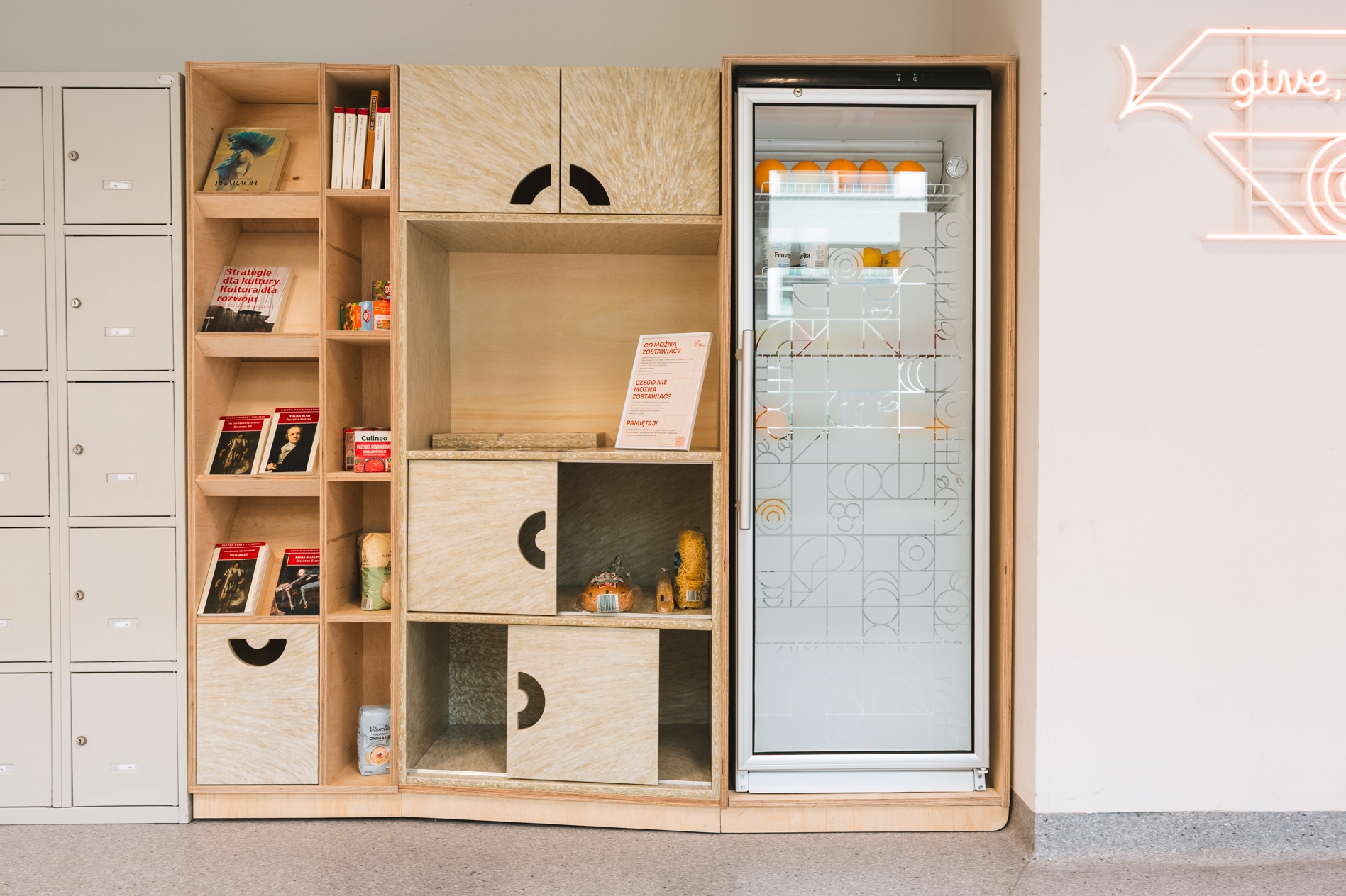 Food sharing corner at SWPS University in Warsaw, featuring a fridge, shelves, and cabinets.