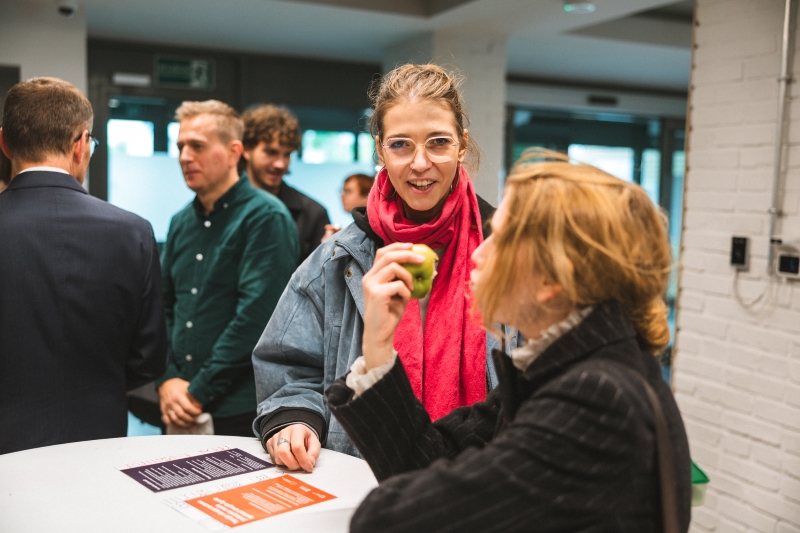 Participant at the food sharing corner opening eating an apple in the foreground.