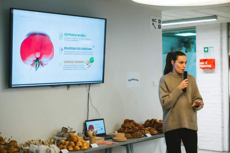 Woman giving a lecture on food storage, with a presentation slide visible in the background.
