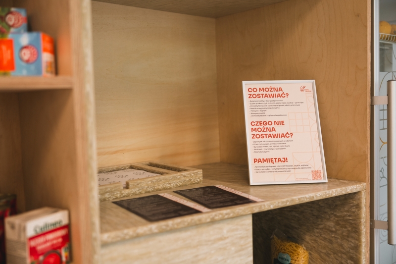 Close-up of a shelf in the SWPS University food sharing corner displaying usage rules.