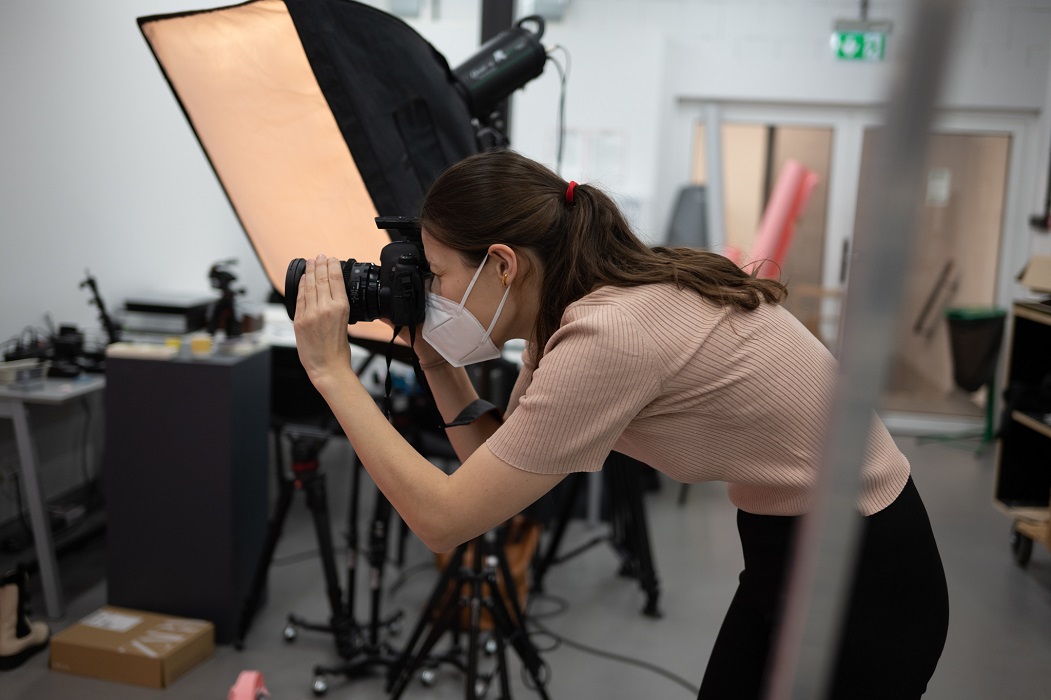 Kobieta w maseczce robi zdjęcie w studio fotograficznym.