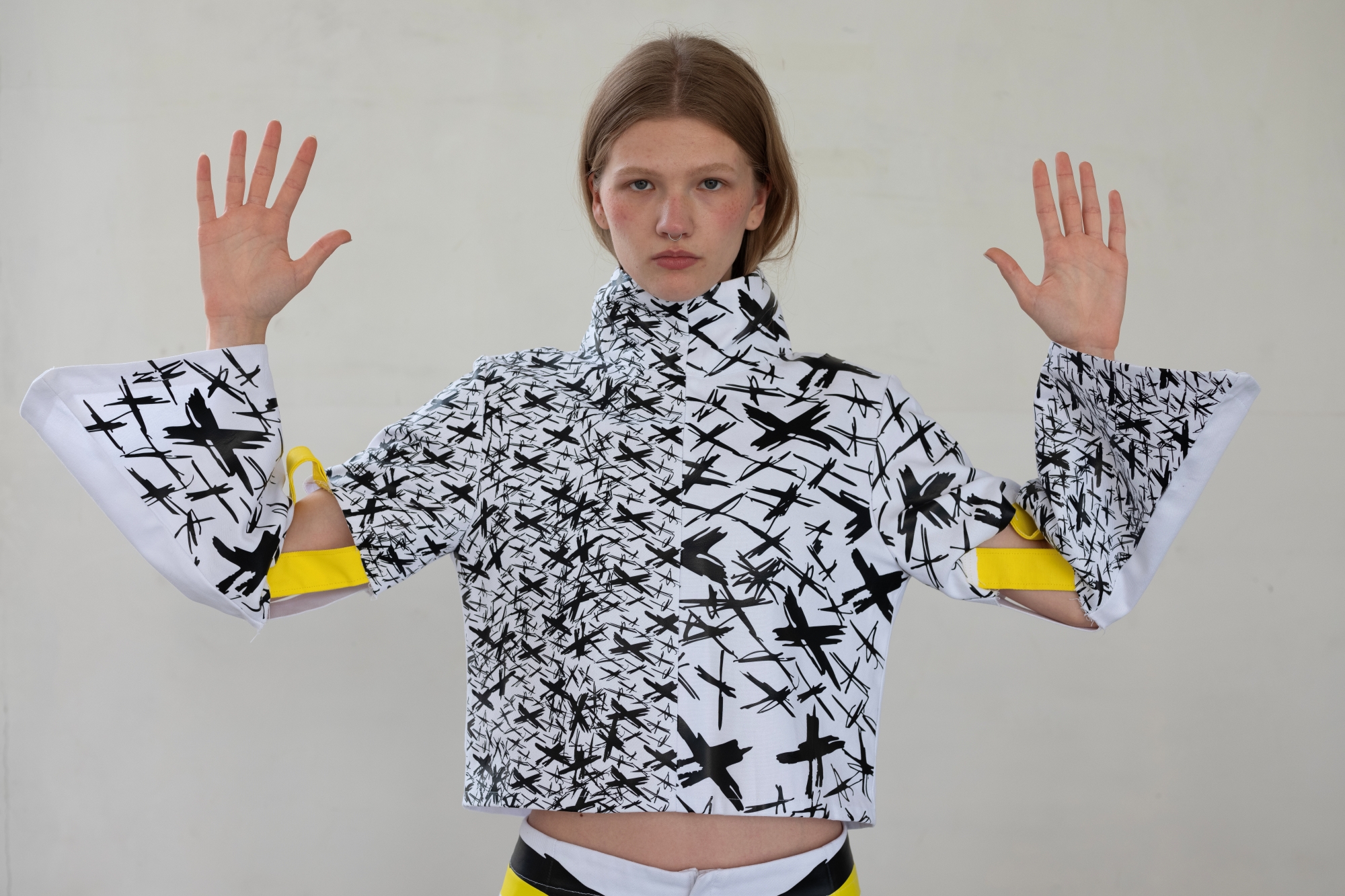 A young woman models a sweatshirt or jacket adorned with an X pattern, designed by Aleksandra Krajewska.