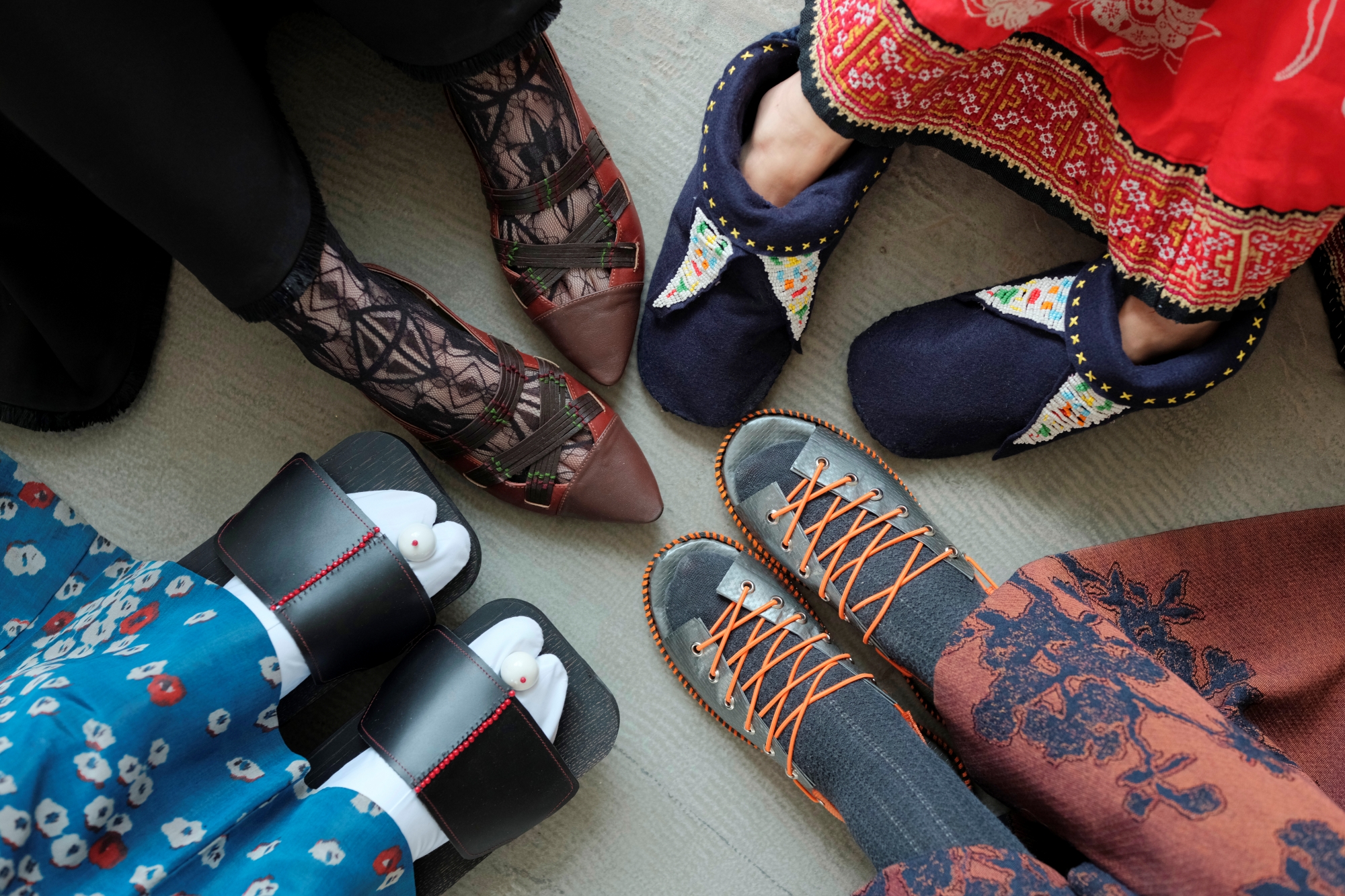 A view from above shows four pairs of feet wearing slippers from different cultures. The slippers were designed by Ina Ignatowicz.