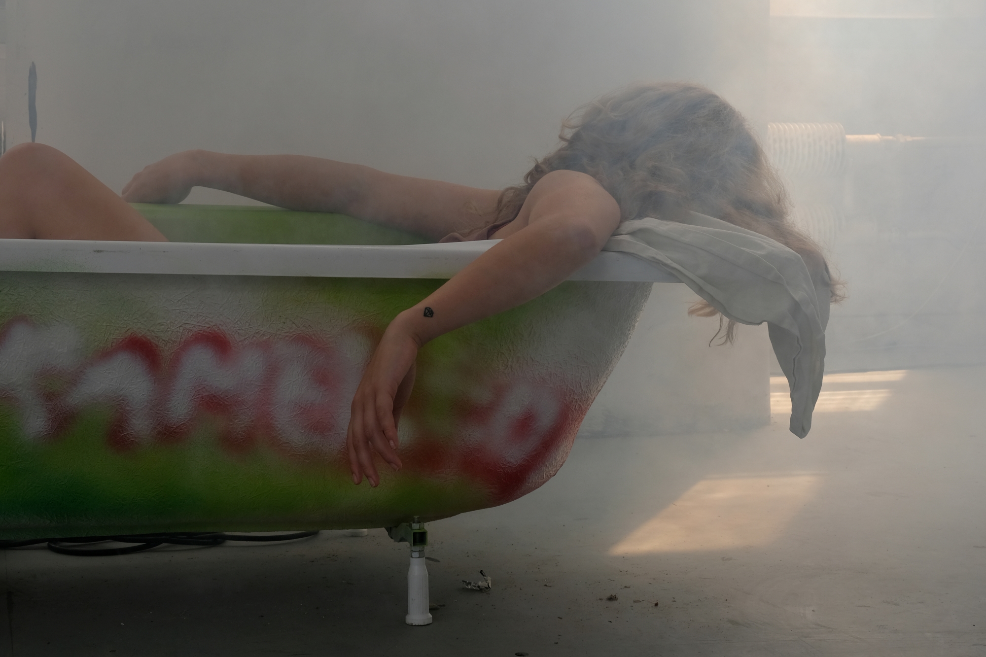 Atmospheric photo of a woman in a bathtub in a smoky room with diffused light