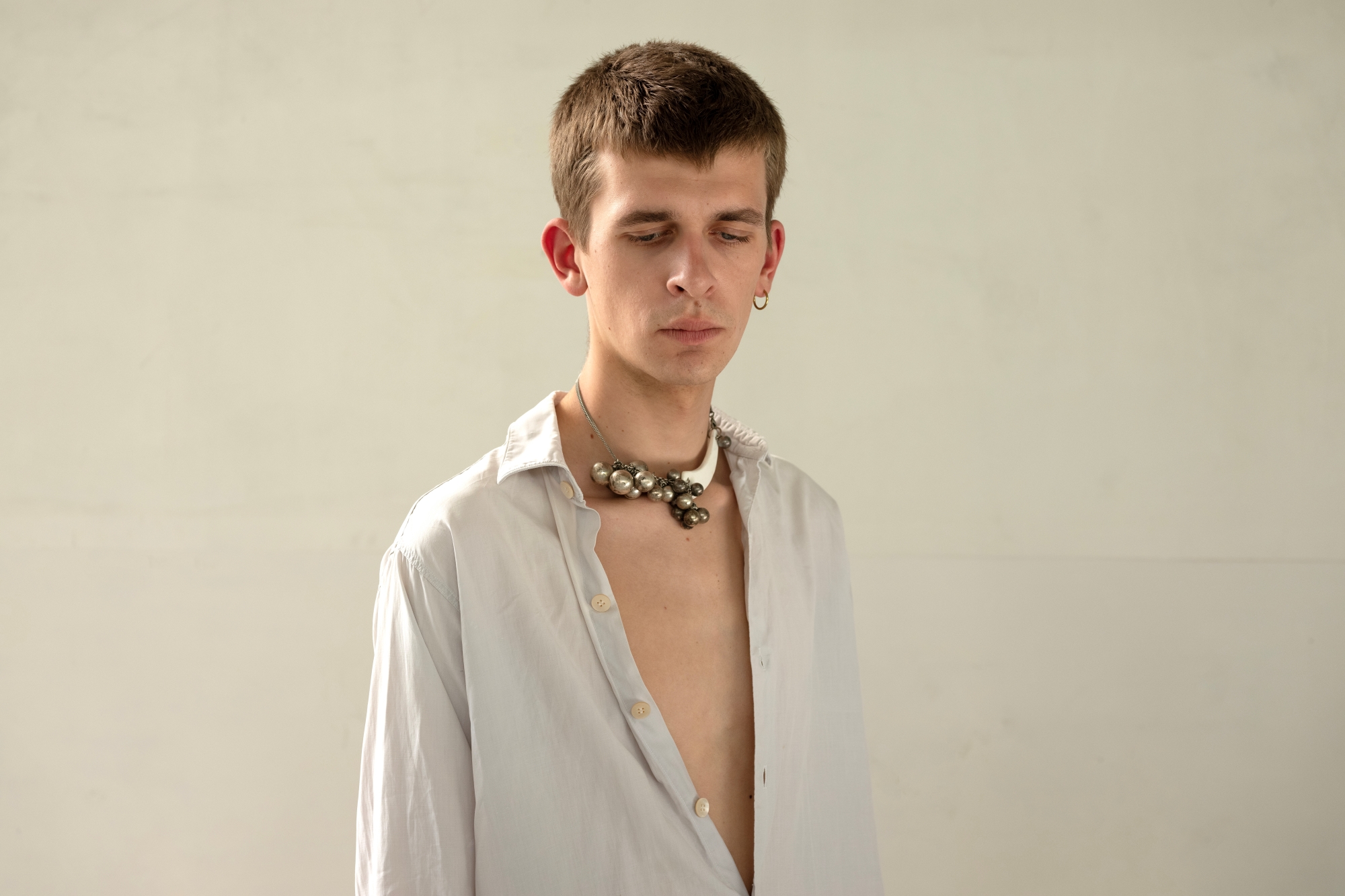 A young man poses wearing a necklace from a collection designed by Maria Kałucka.