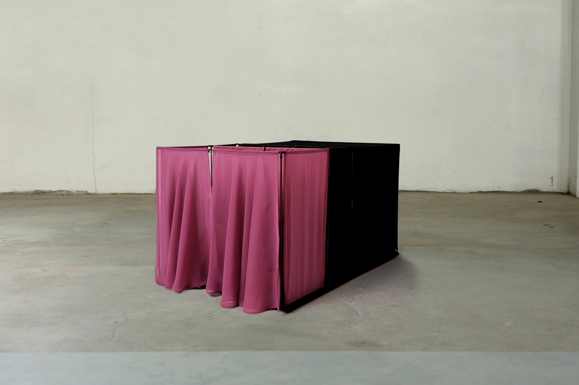 A separate space within a concrete room, hidden behind curtains.