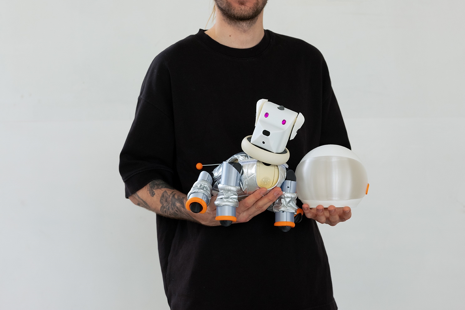 A man holds a robotic dog in space suit designed by Julia Kellner.