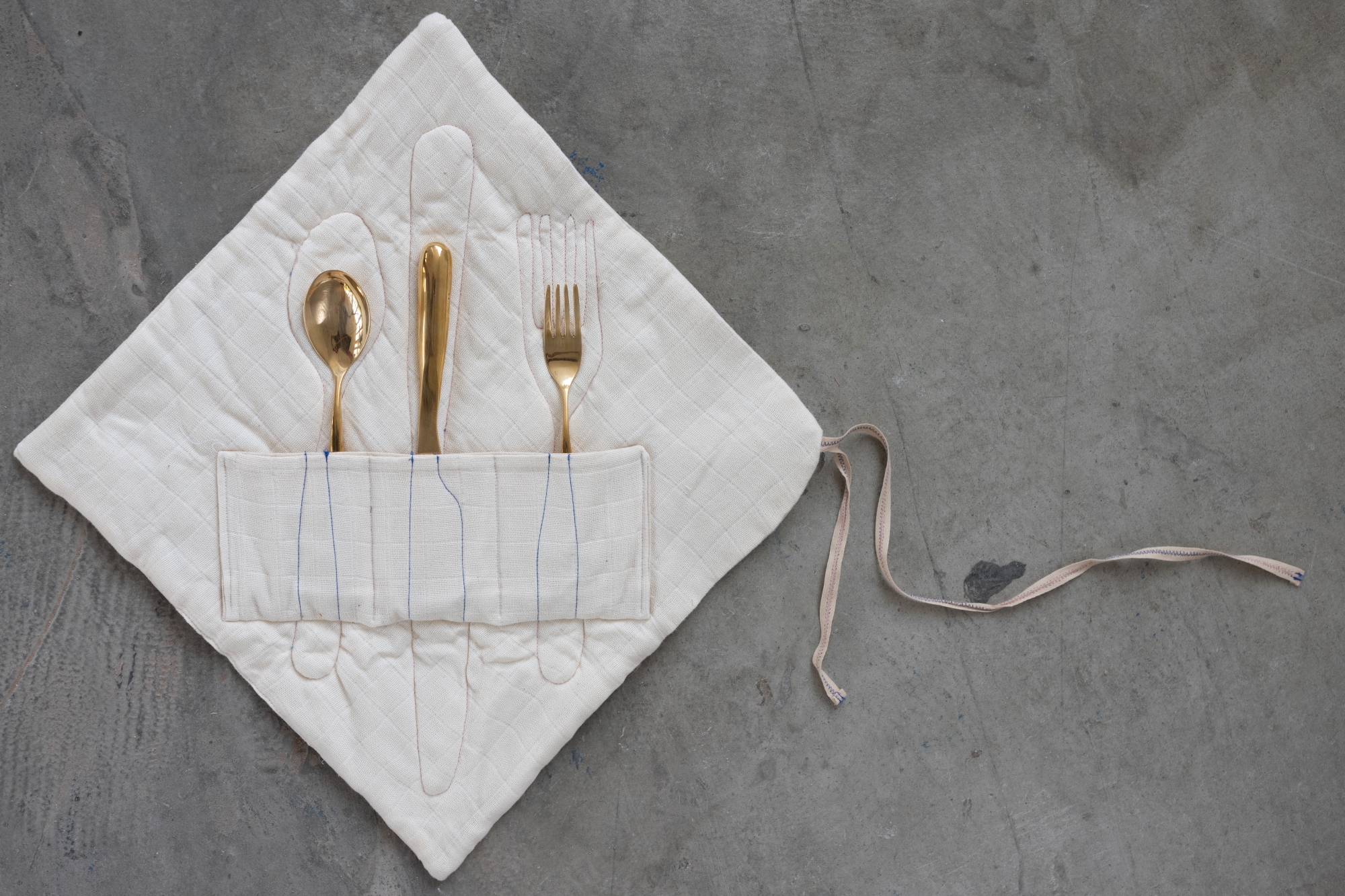 A set of brass cutlery in a fabric bag designed by Franciszka Popławska.