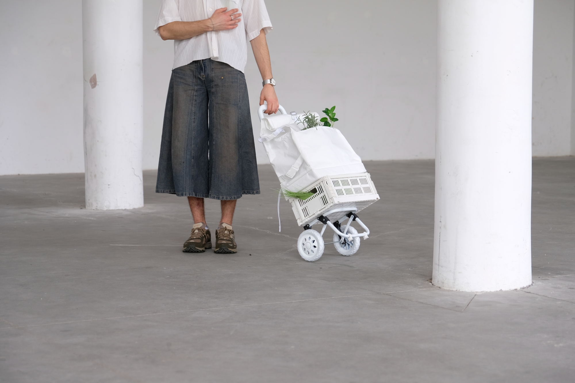A person standing next to the shopping cart, framed from the shoulders down.