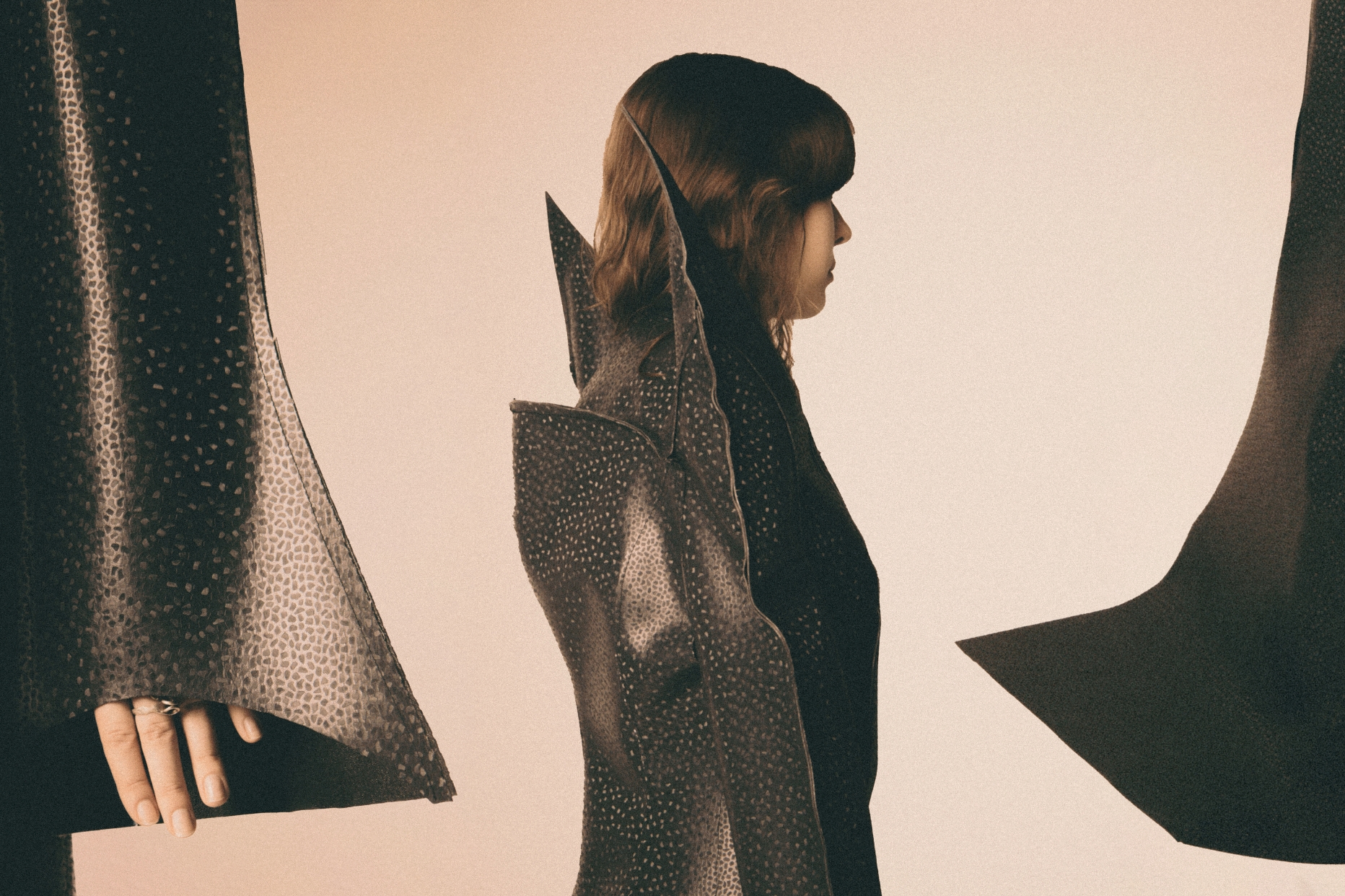 Close-ups of three elements of the roofing membrane coat: extended sleeves, a stand-up collar reminiscent of a vampire's cloak, and a train