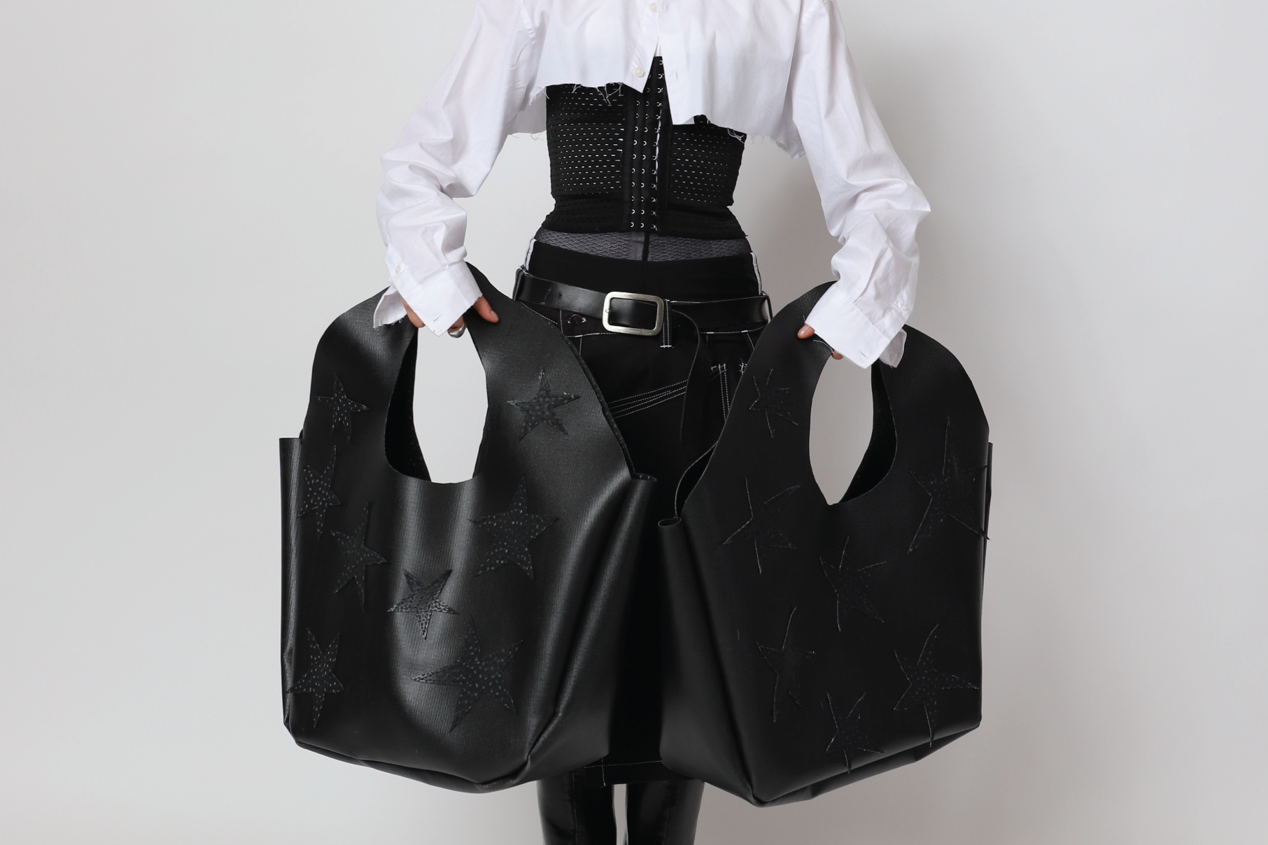 Model presenting two big handbags made of roofing membrane